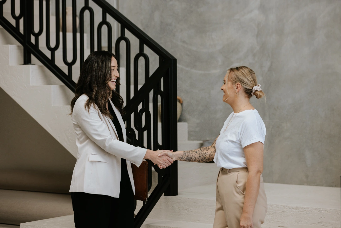 Smiling professional female lawyer shaking hands with blond haired woman