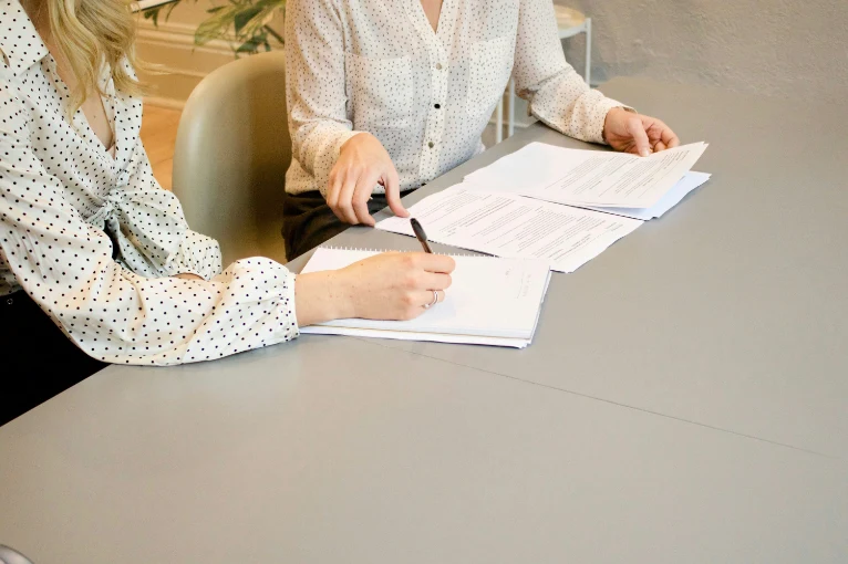 Legal paperwork on table with hands pointing to documents