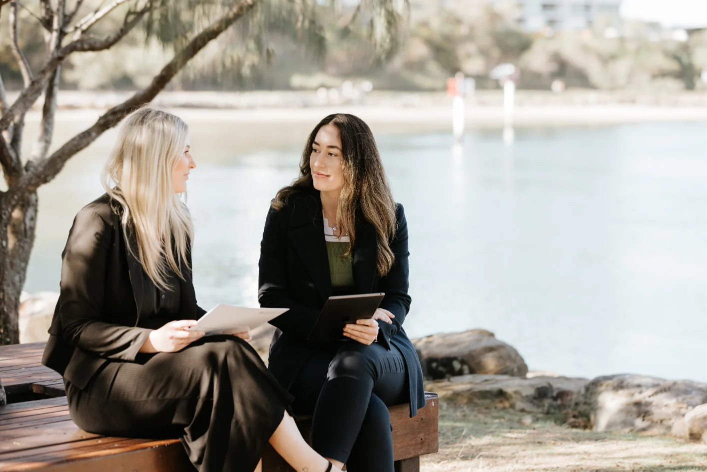 Two women discussing a legal matter by the lake