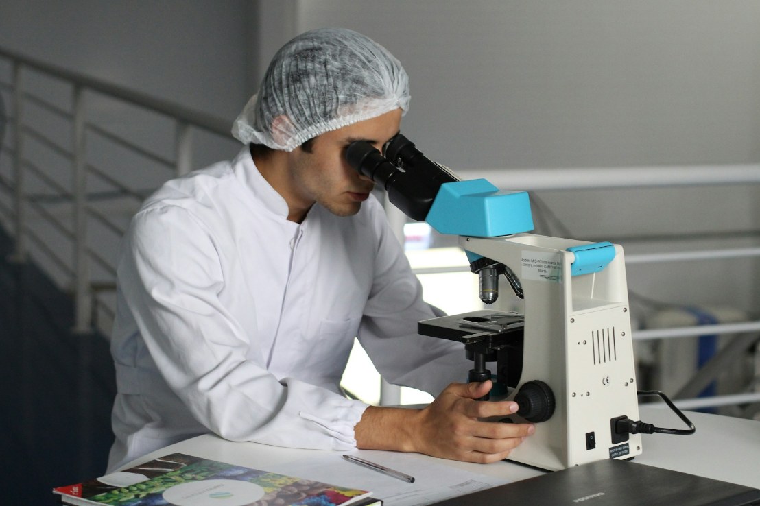 Lab technician inspecting sample in microscope