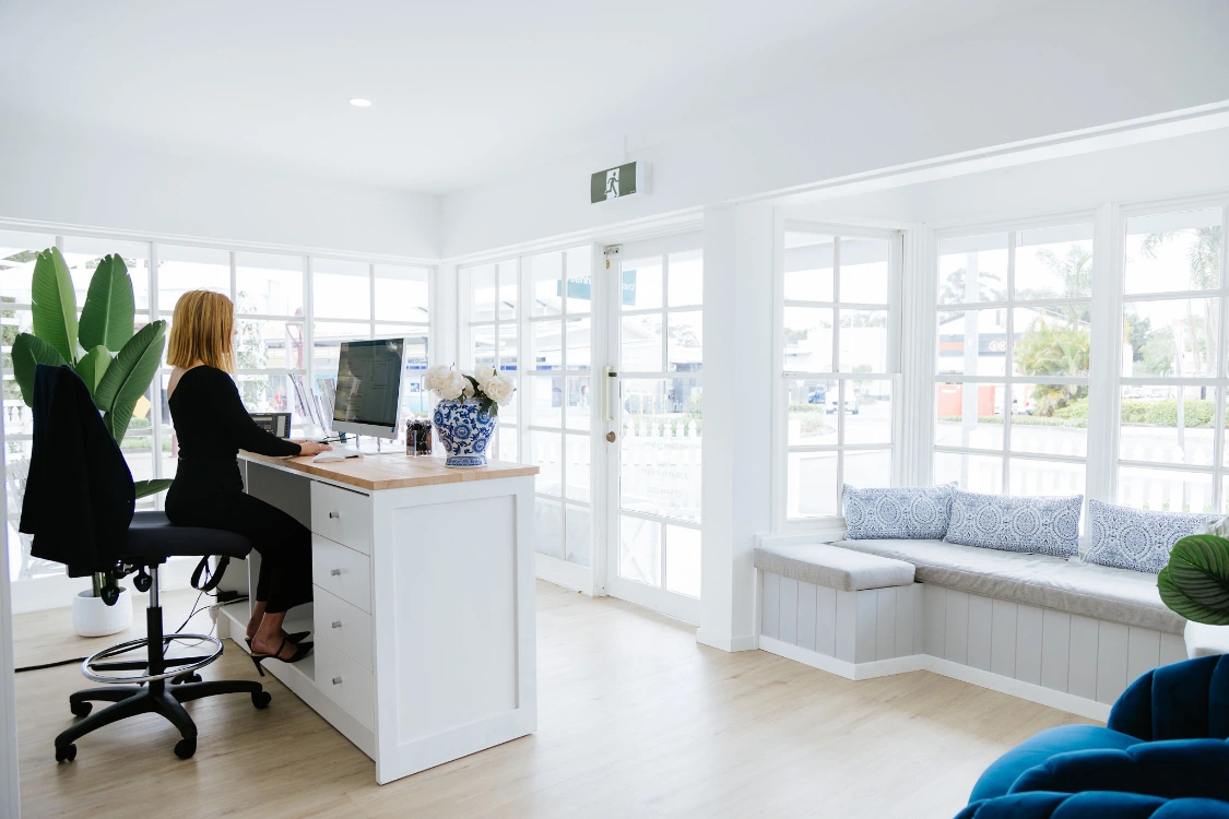 Female receptionist sitting behind desk in bright lit office