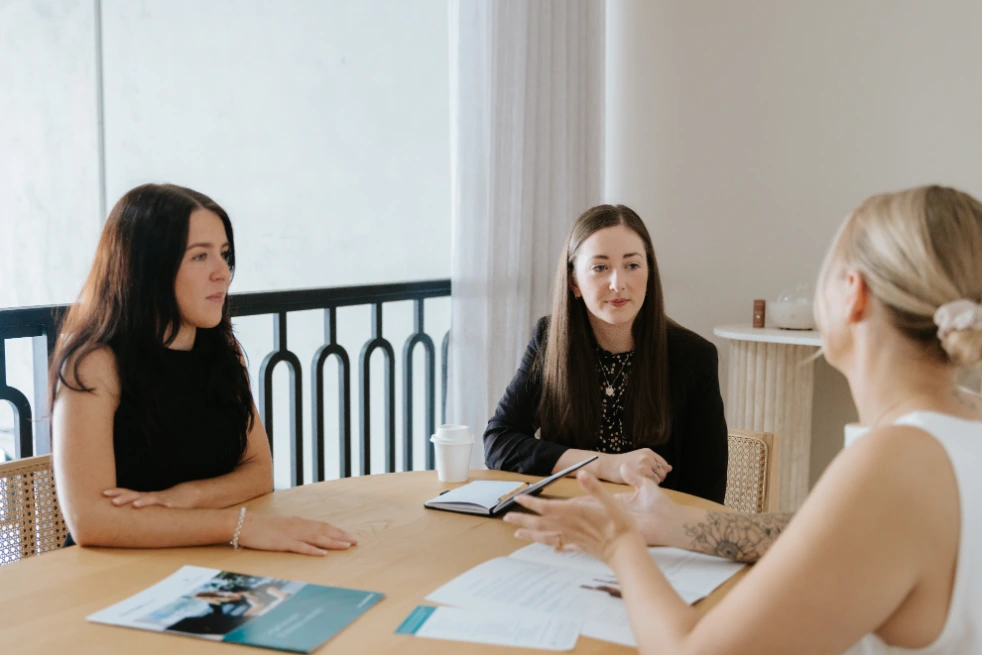 Two female solicitors talking to a client at a board room table