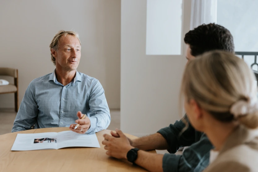 Blond male solicitor in blue button up shirt talking to clients