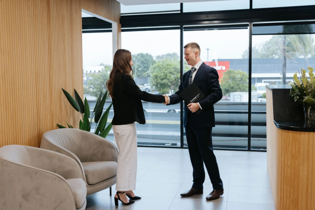 Male solicitor in suit shaking hands with long haired female