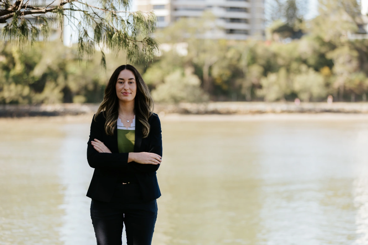 Tall brunette lawyer standing in front of lake facing the camera