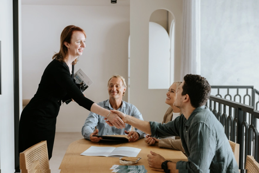 Female red haired estate solicitor shaking hands with brunette man in nice shirt