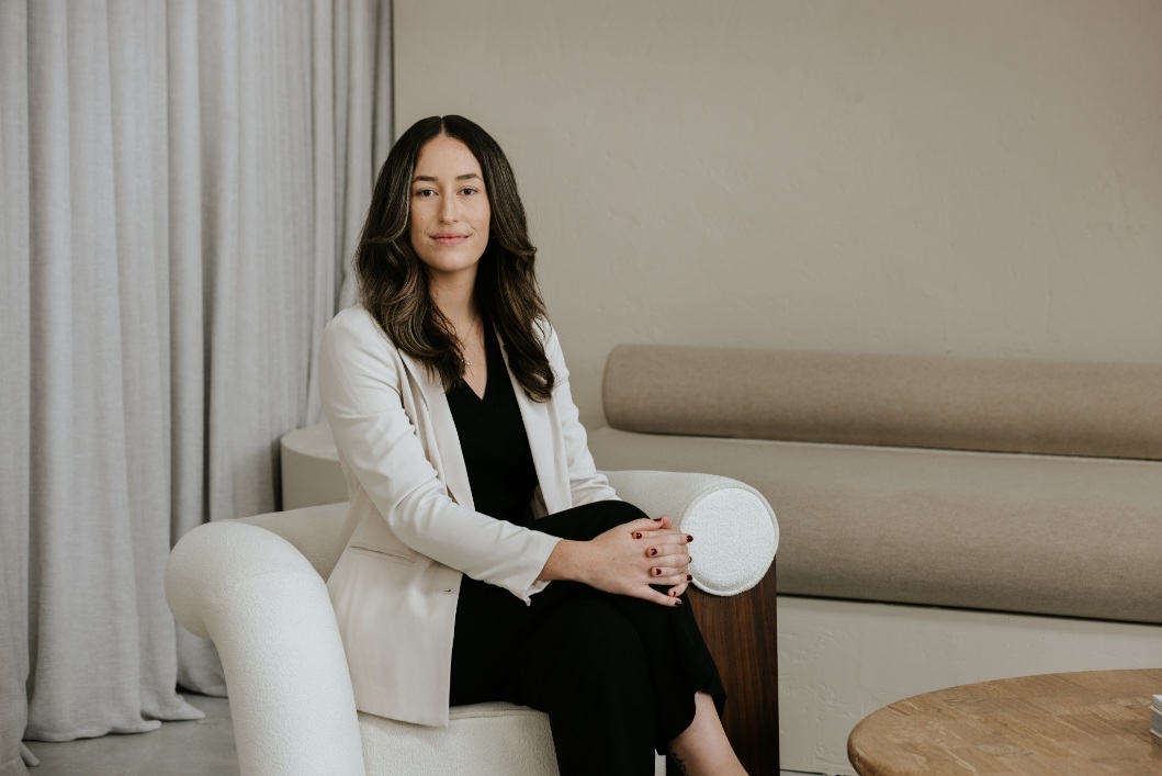 Smiling female solicitor with dark long hair and white suit coat