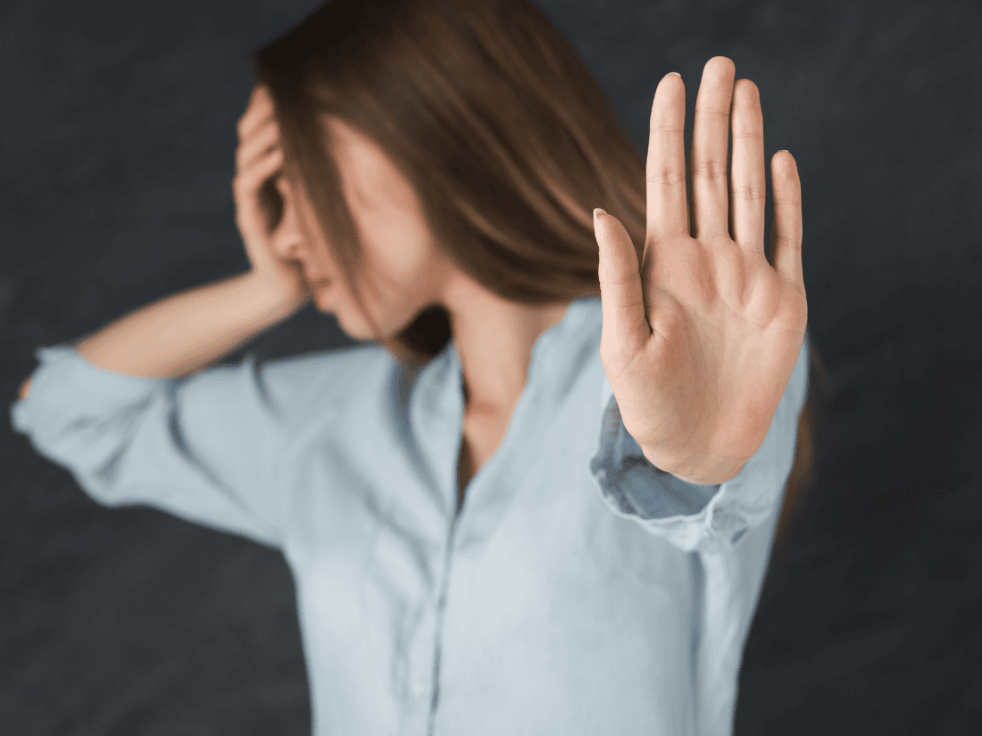 Brunette female holding her head and showing the palm of her opposite hand